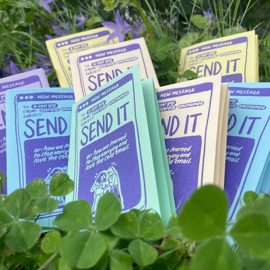 Several multicolored copies of mini zine SEND IT sitting on clover.